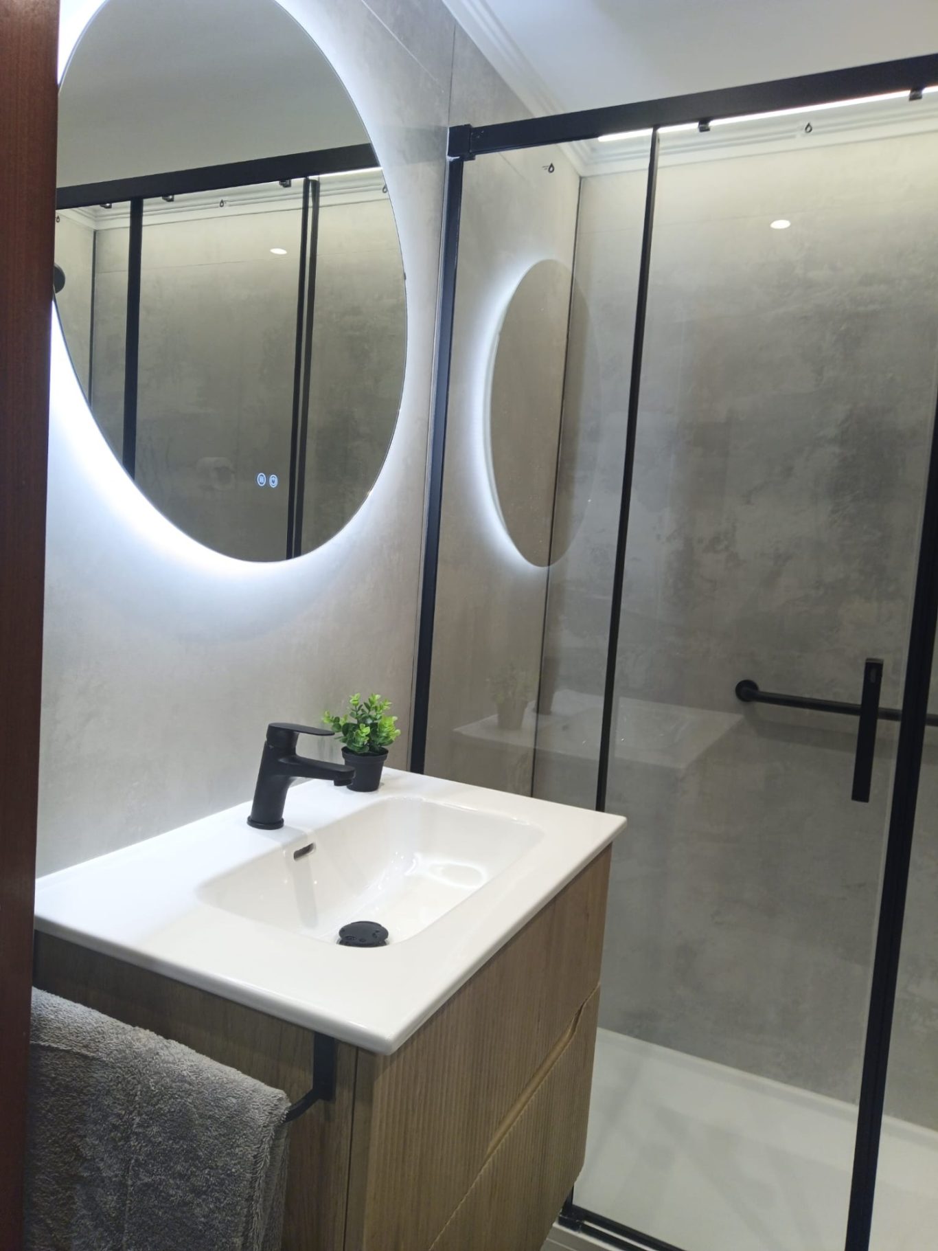 mueble en madera estriada y espejo redondo retroiluminado