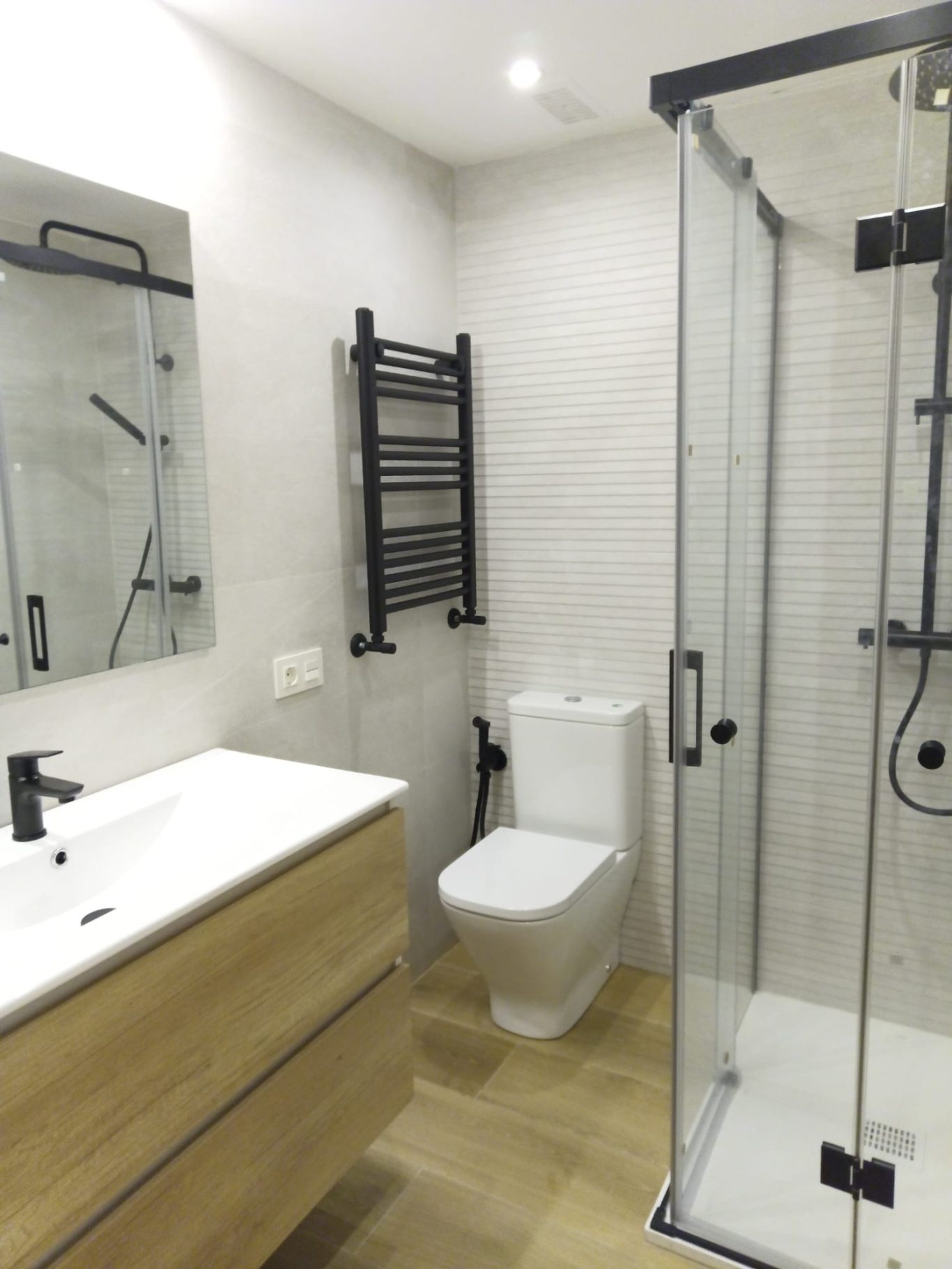 REFORMA GENERAL ducha pequeña con mampara plegable y corredera. Radiador toallero negro a juego